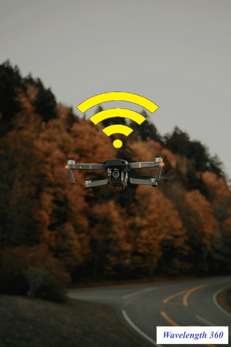 A drone flying over a winding road with autumn trees, a yellow Wi-Fi signal icon superimposed above it. The image represents wireless antenna technology in drones.